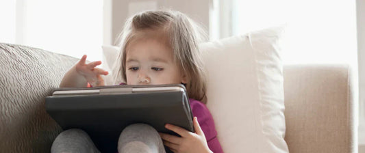 Kind sitzt auf dem Sofa mit einem Tablet