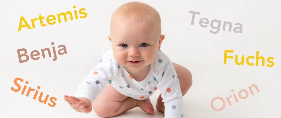 Ein lächelndes Baby in einem weißen Strampler mit bunten Punkten sitzt auf einem weißen Hintergrund. Um das Baby herum sind verschiedene Namen in unterschiedlichen Farben und Schriftarten angeordnet