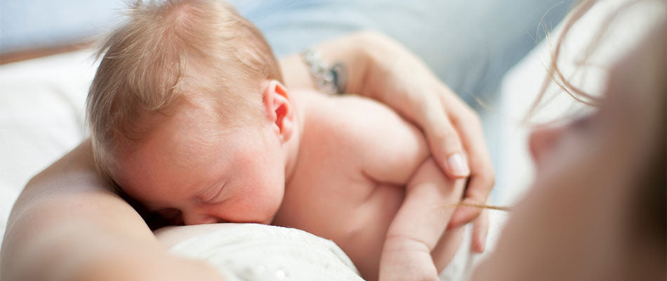 Mutter stillt ihr neugeborenes Baby, das friedlich an ihrer Brust liegt.