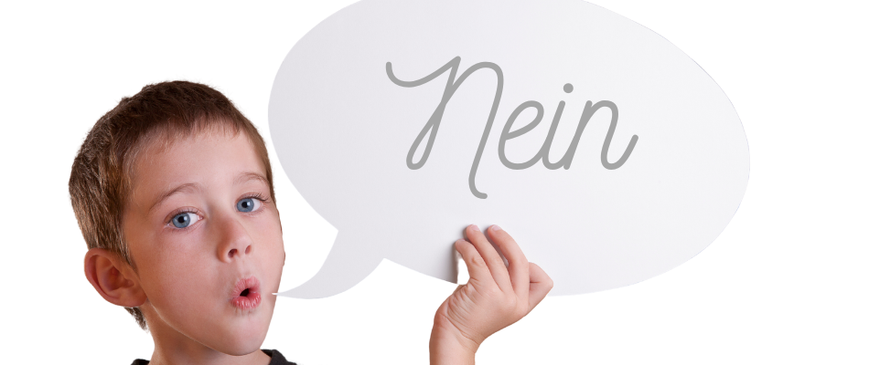 Ein Kind hält eine Sprechblase aus Pappe, auf der "Nein" steht. Es hat den Mund leicht geöffnet und schaut direkt in die Kamera.