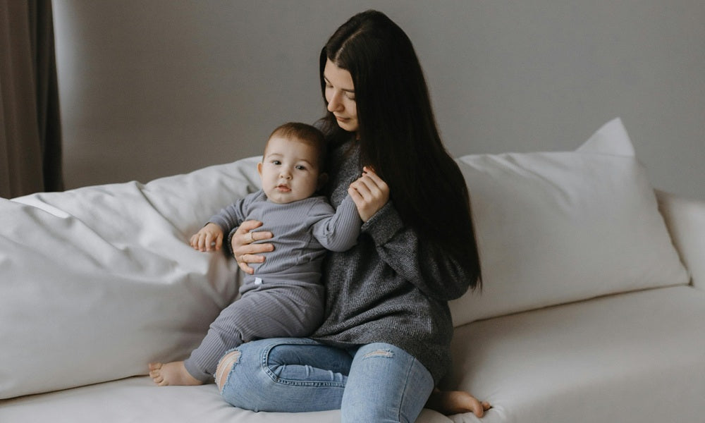 Mutter sitzt mit ihrem Baby auf dem Sofa