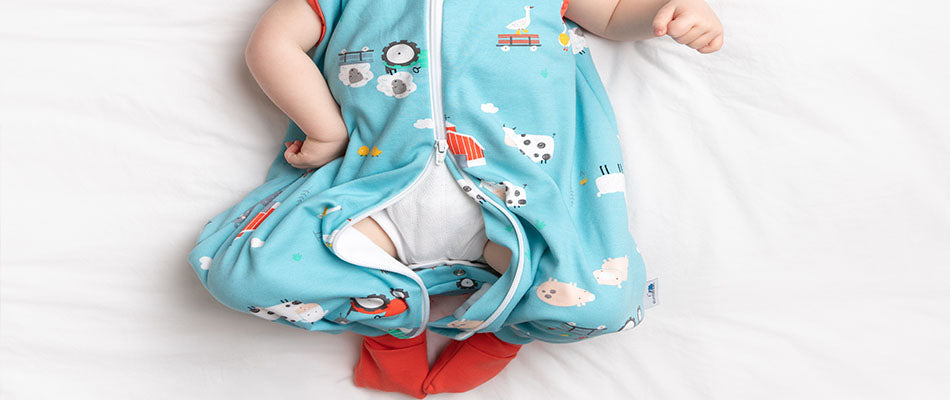 Ein Baby in einem Schlafsackmit Beinen mit Bauernhofmotiven.