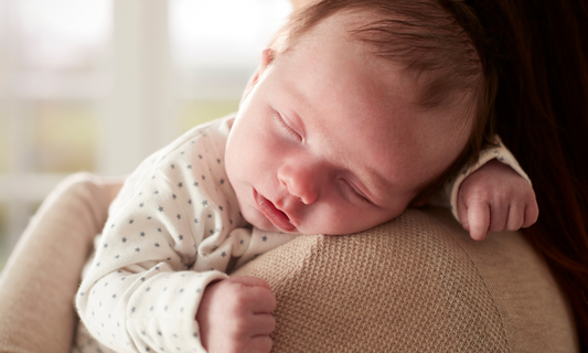 Schlafendes Baby auf dem Arm der Mutter